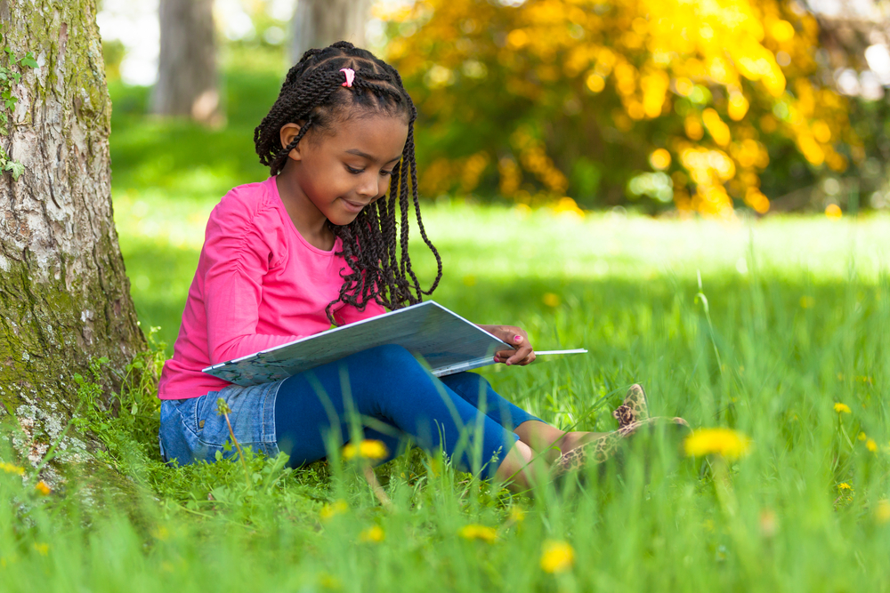 Young girl learning to read outside
