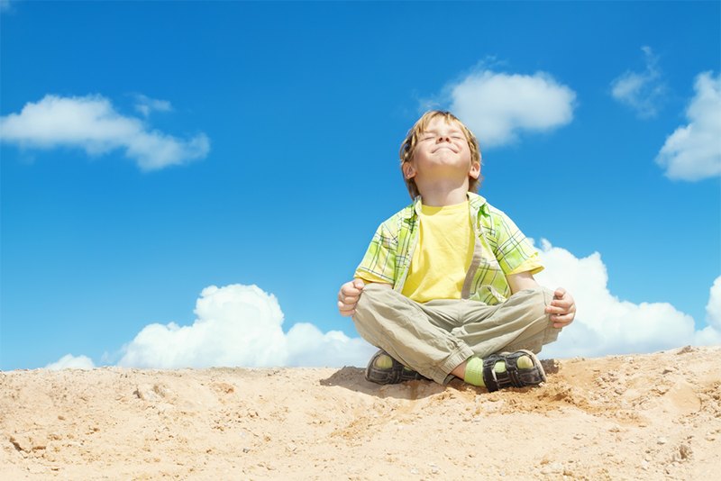 Young kid meditating outdoors

