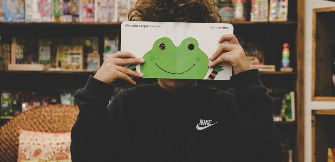 child holding up a board book in front of their face