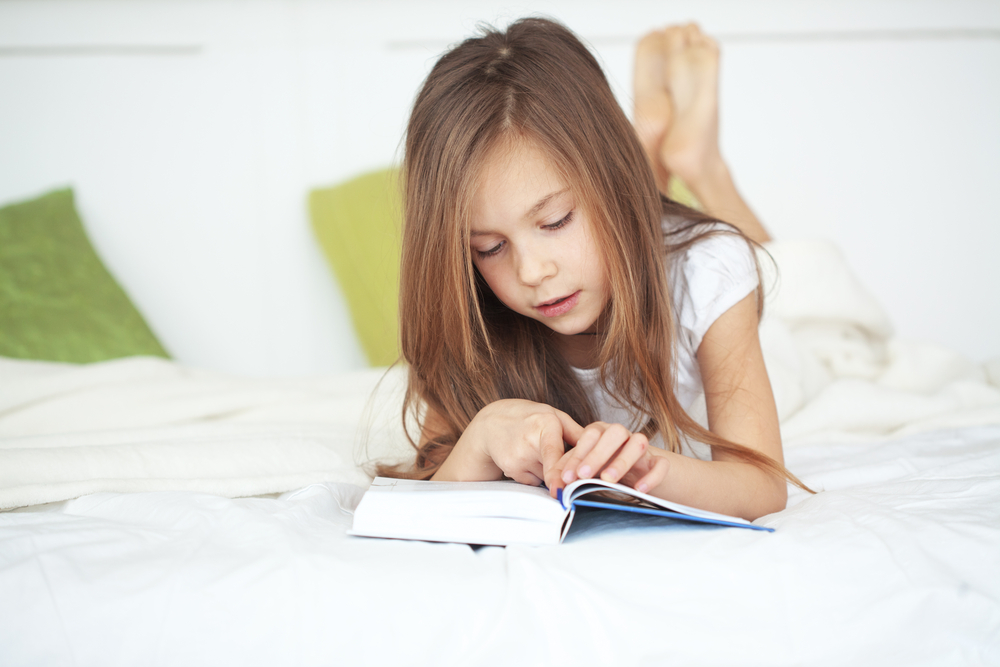Child using her reading strategies to read a book