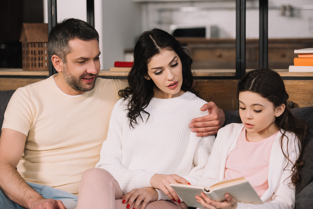 Parents helping daughter read aloud