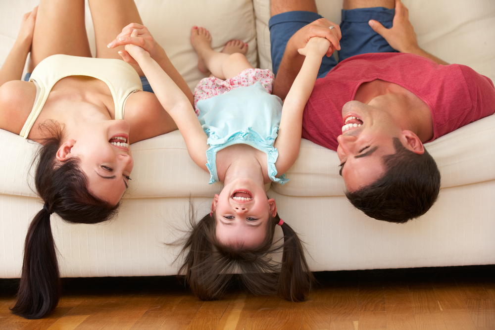 Family Lying Upside Down On Sofa With Daughter