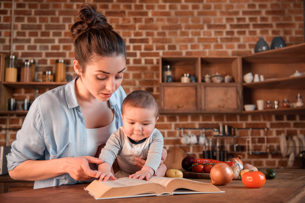 mom showing baby a book in the kitchen