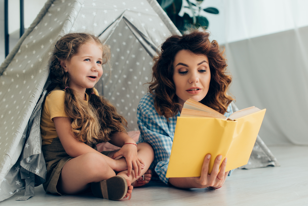 Mom and daughter reading in a living room tent