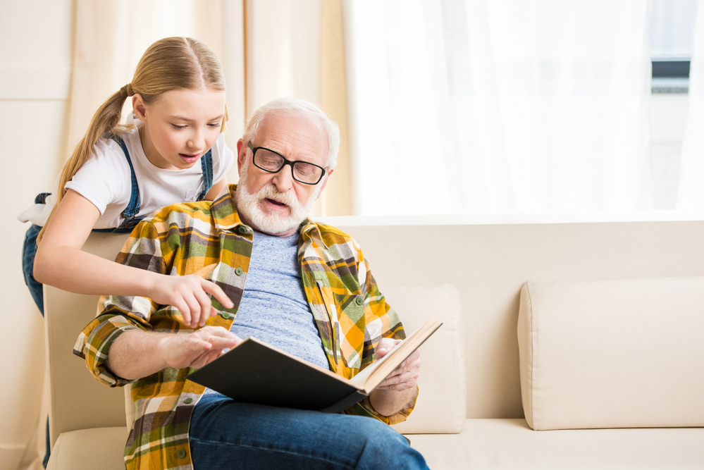 Young girl reading with her grandfather