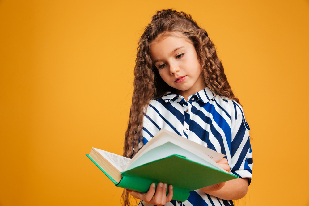 Concentrated little girl reading a book