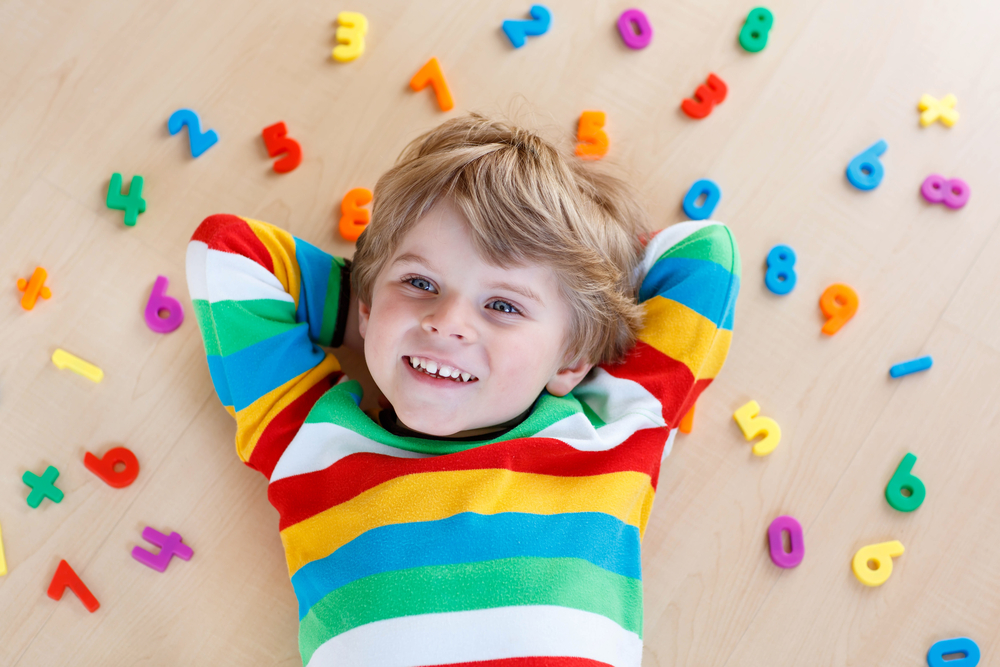 Kid laying on ground with colorful plastic numbers