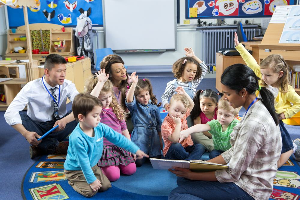 Teachers reading book to preschoolers in classroom