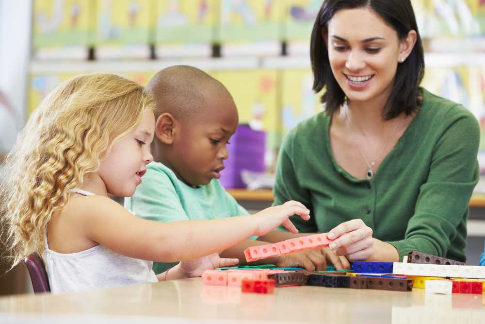 Elementary kids Counting With Teacher In Classroom