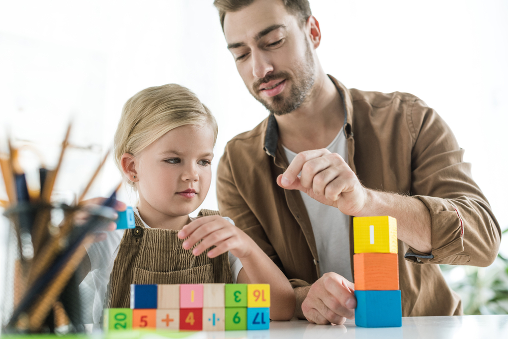 Dad and daughter playing number matching games with blocks