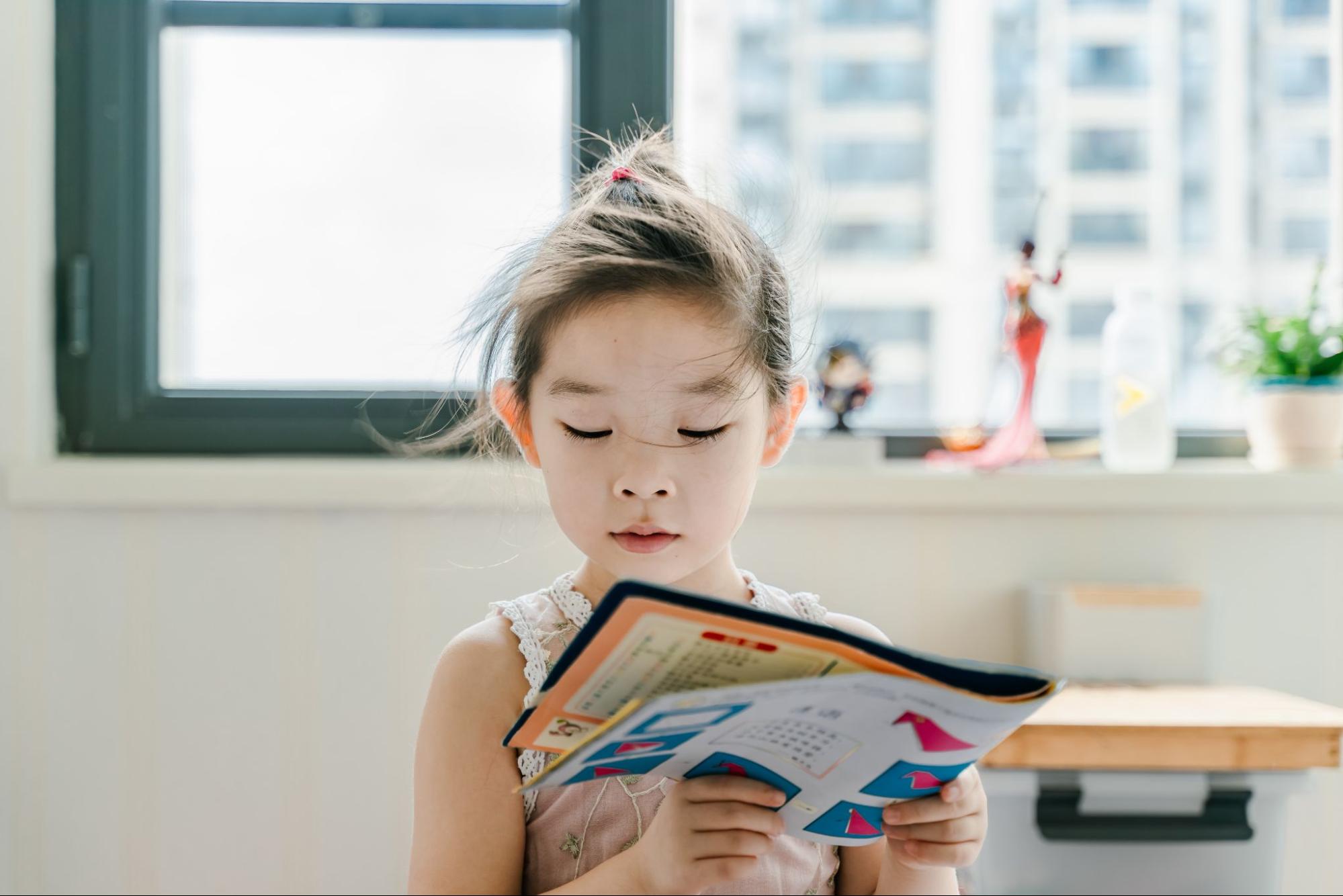 A young girl reading a book at school