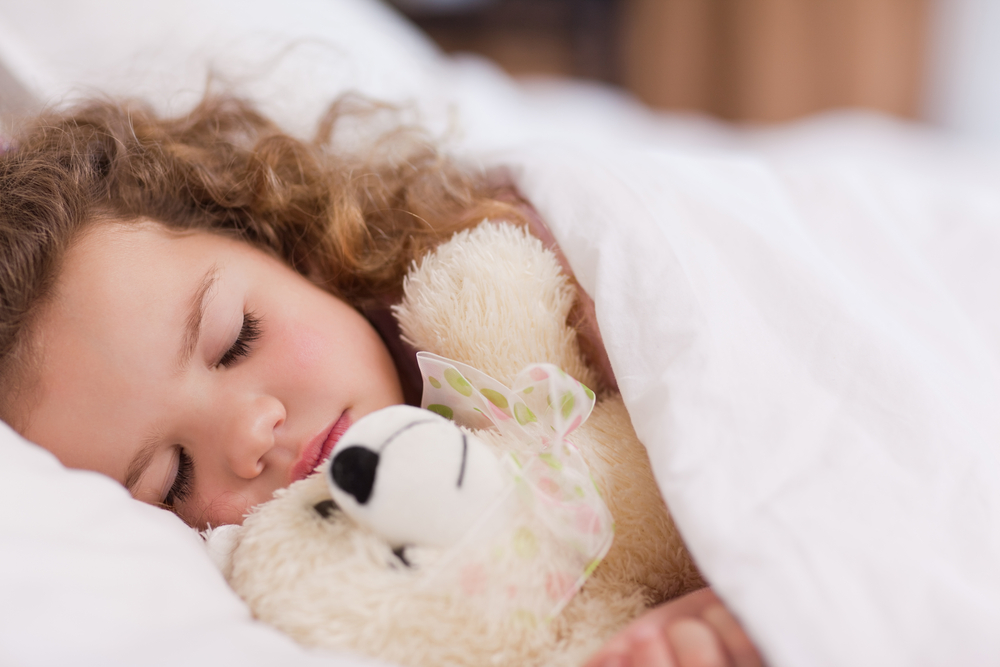 child sleeping with her teddy bear as part of her bedtime routine