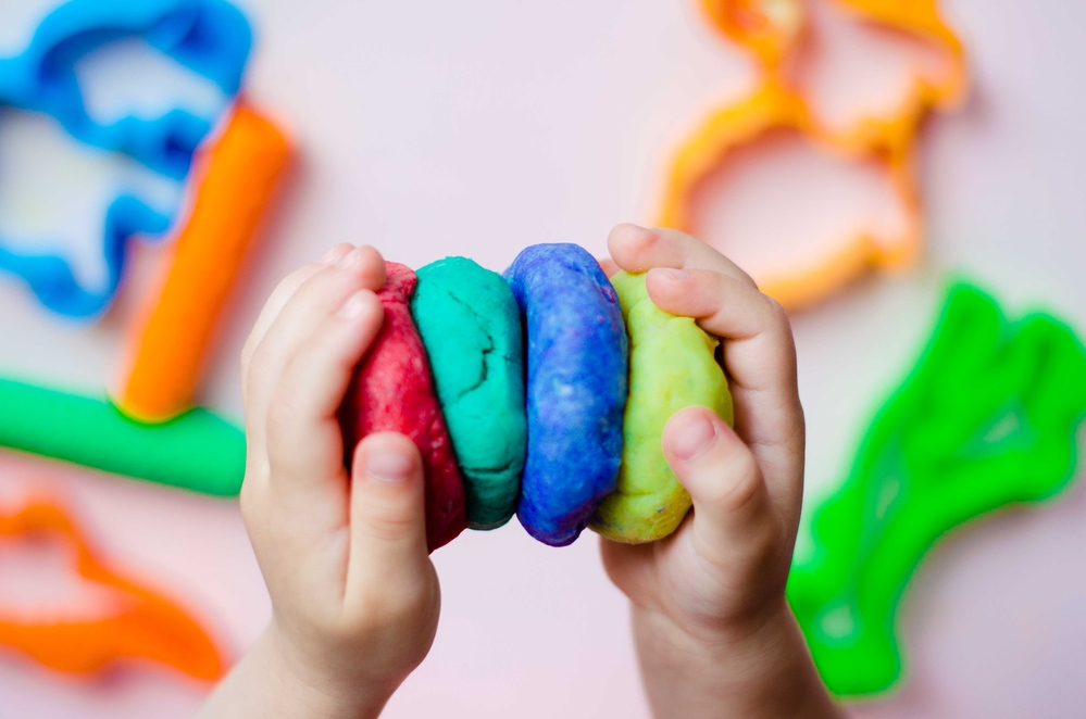 kid holding different colored Playdough in hands