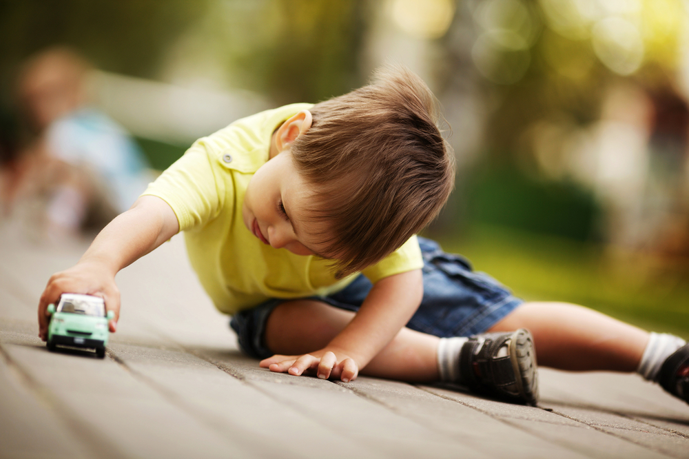 Young boy learning through play with toy cars