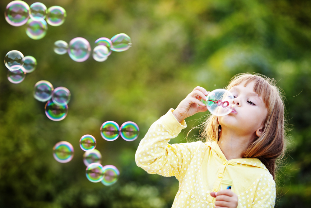 A young girl learning through play with bubbles