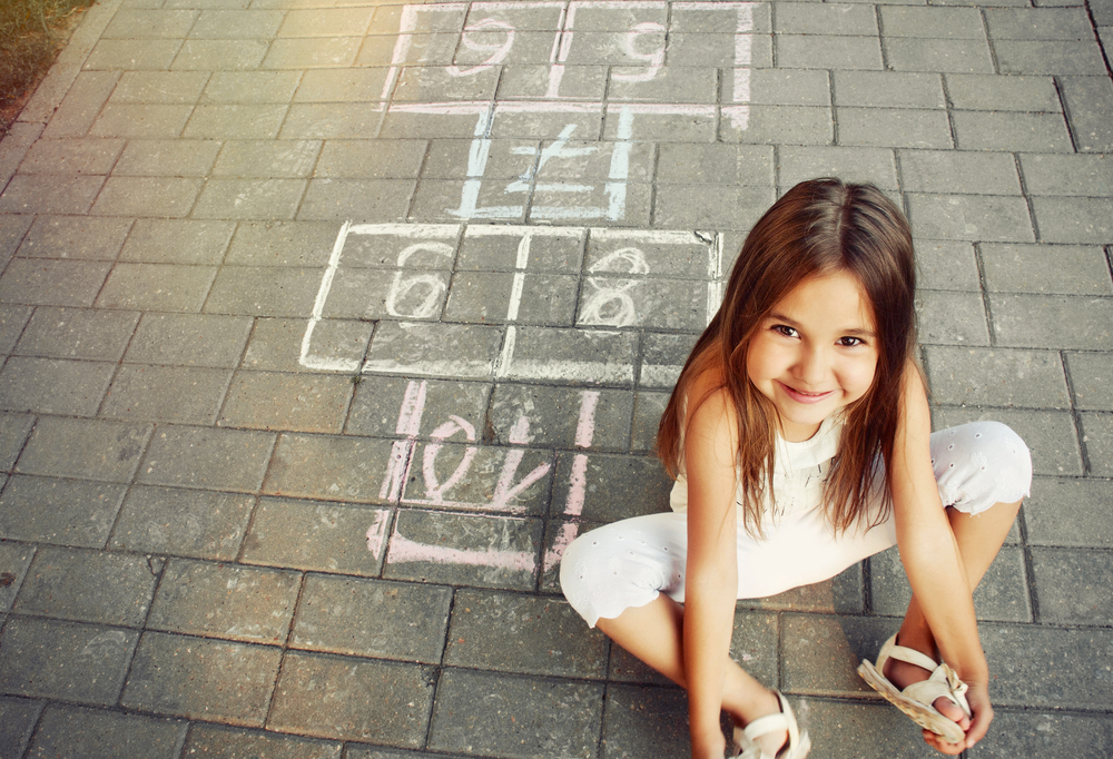 young girl sitting on a hopscotch court
