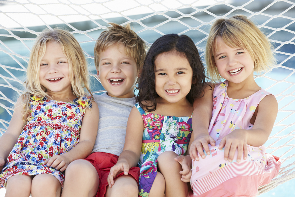 Four Children Relaxing In Garden Hammock Together