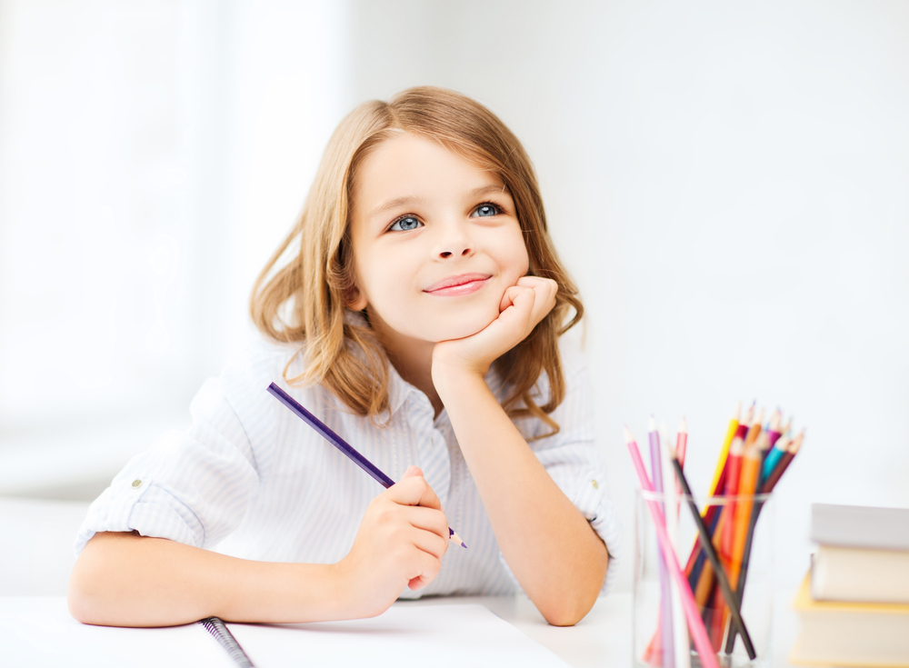 little student girl drawing with pencils at school