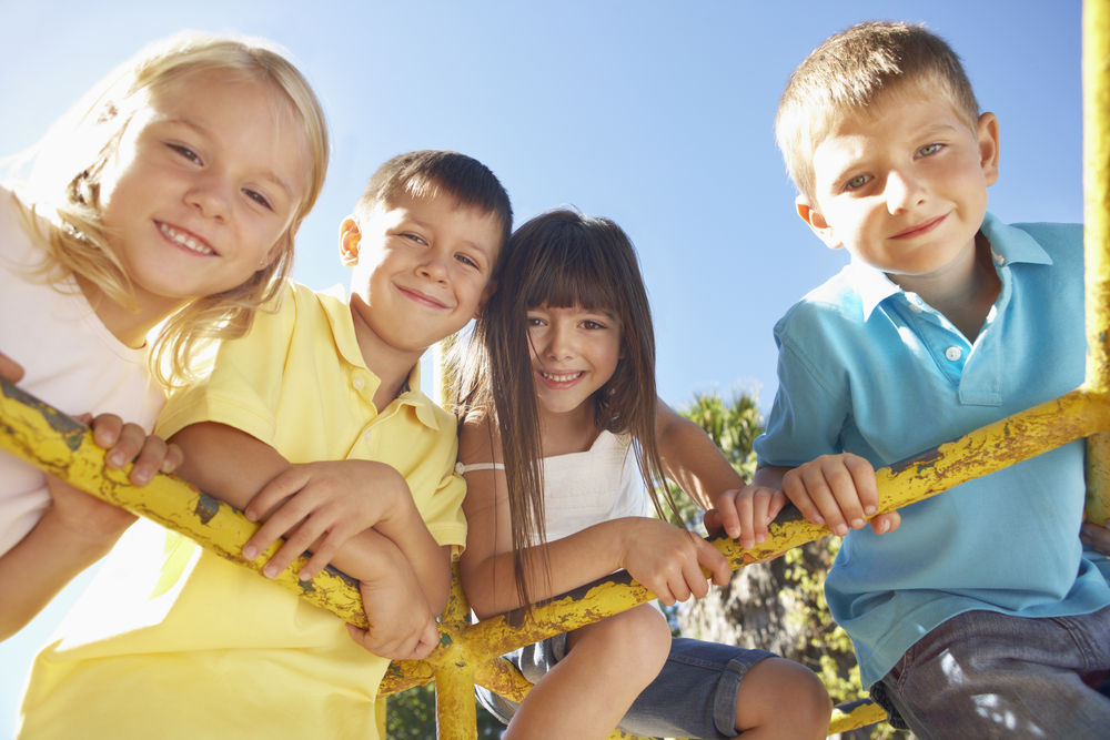 4 kids hanging on a jungle gym