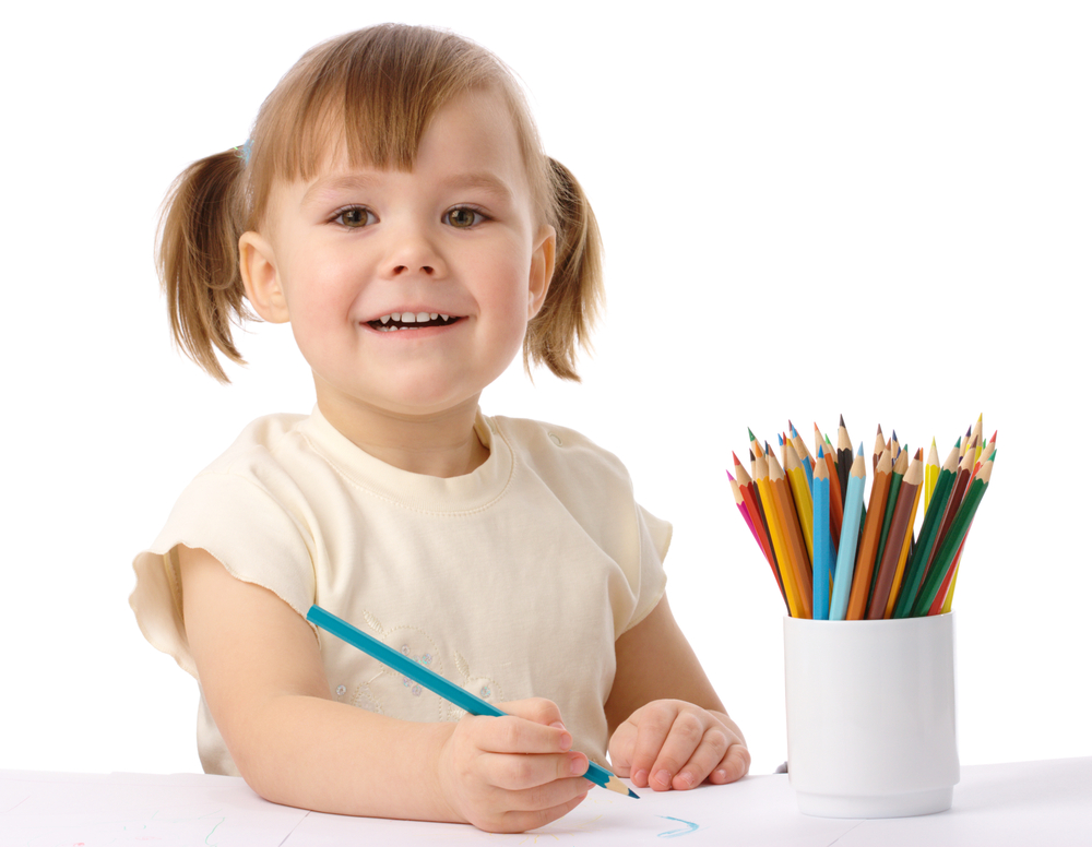 Cute child draws with color pencils, isolated over white