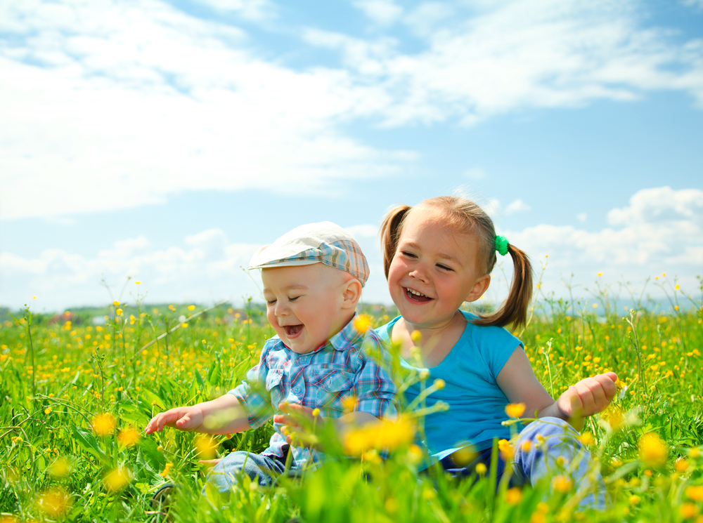 Two children (a girl and a boy) are having fun on green meadow