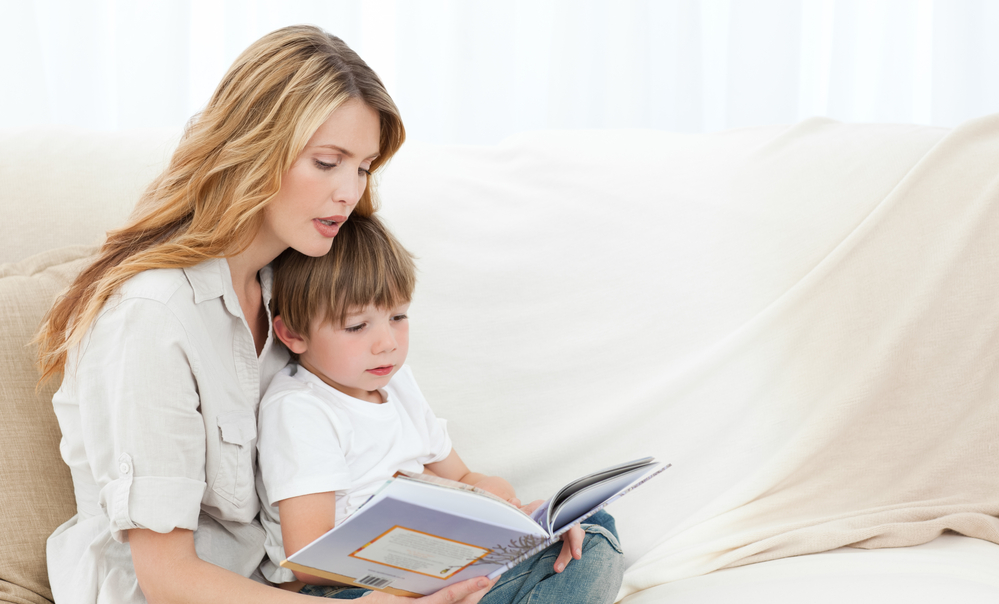 Mother reading with her son on the sofa