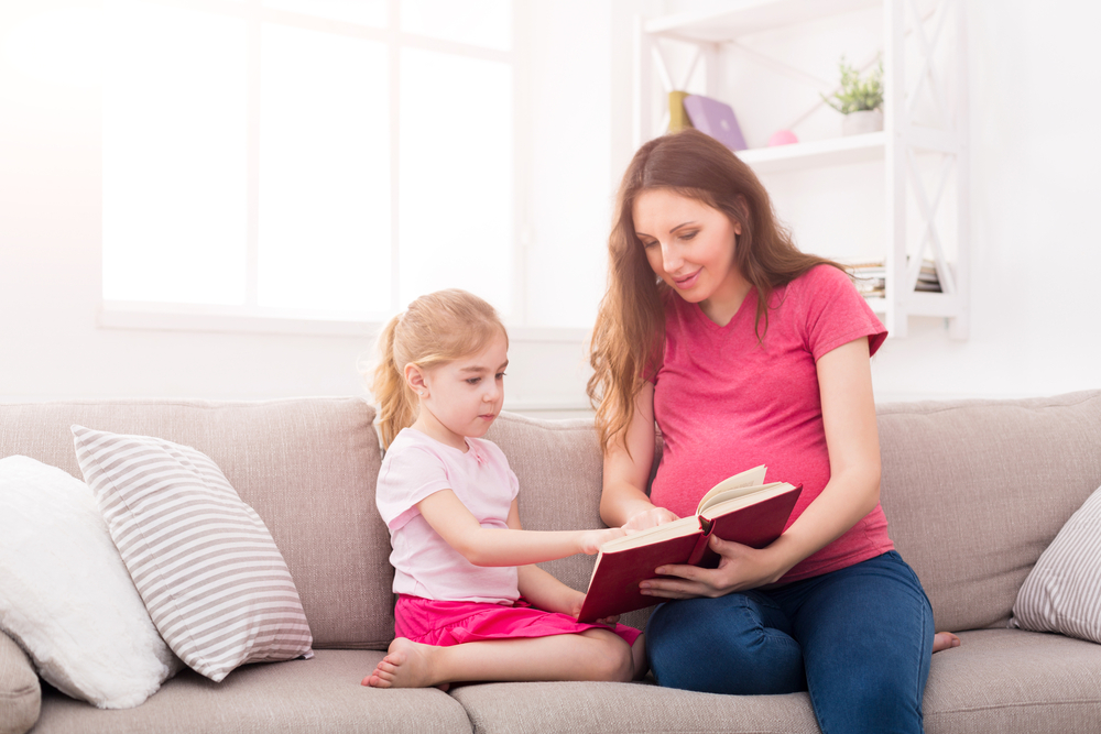 Pregnant mom reading to her daughter