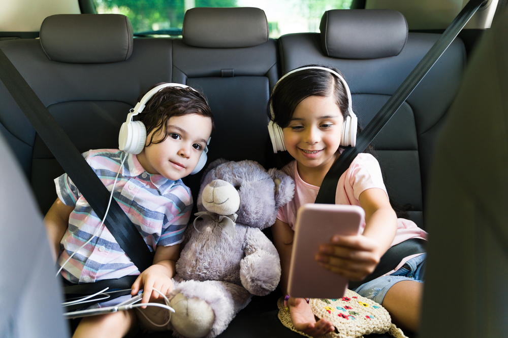 Two kids on a road trip playing on a tablet
