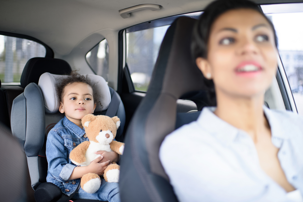 Young kid being entertained by a stuffed animal in the car