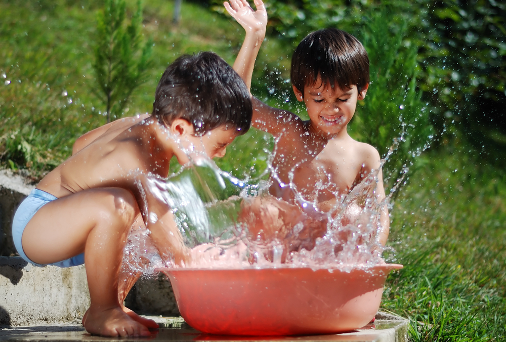 Two kids playing with water oustide