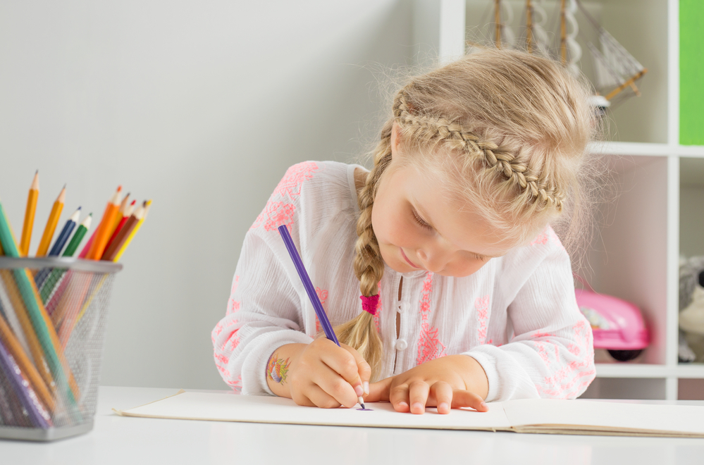 Young girl coloring with colored pencils