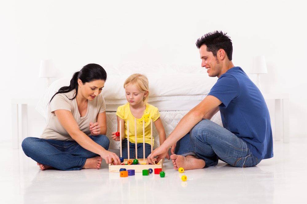 happy family playing fun educational games on bedroom floor