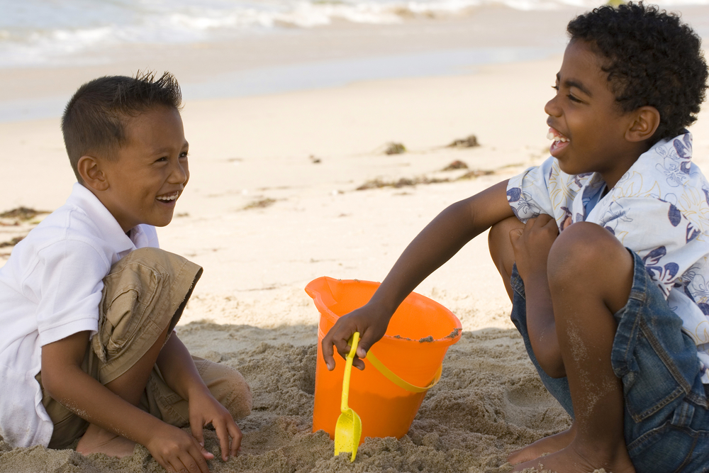 Happy kids playing in the sand at the beach.