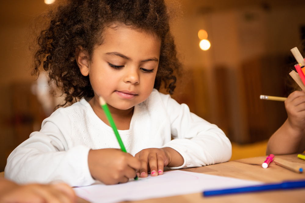 Young girl coloring with colored pencils