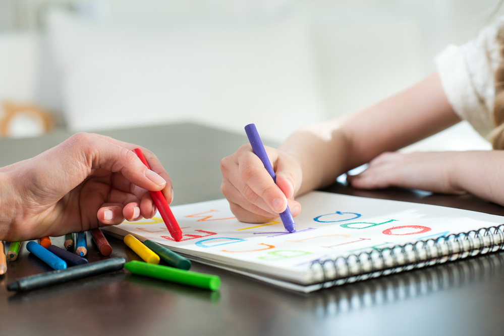 Young kid learning letters by tracing