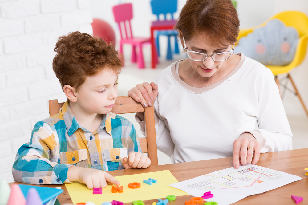 Young boy learning new words playing with colorful letters