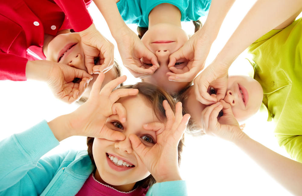 kids looking down in circle with hands around eyes