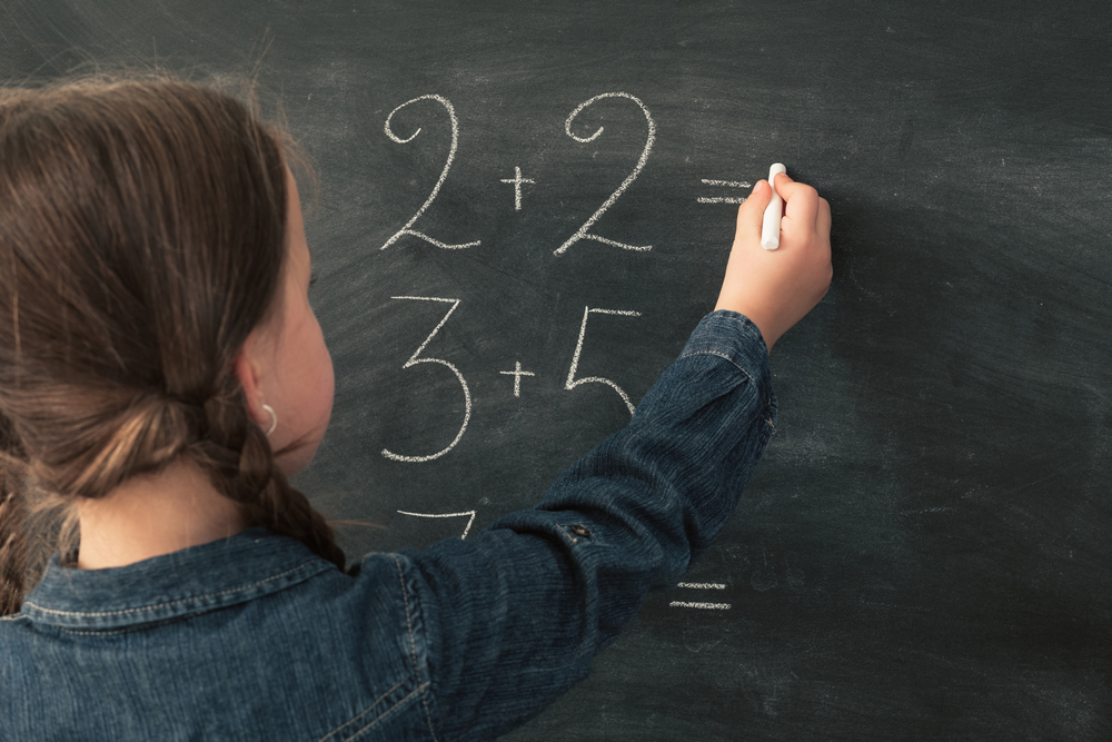 Kid doing math on a chalkboard