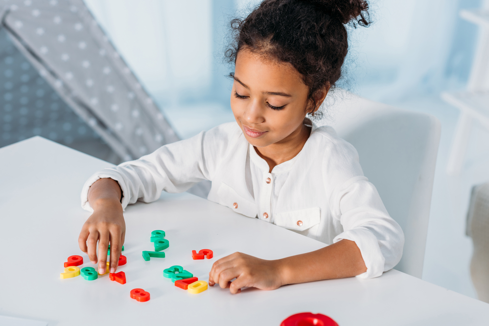 Young girl playing with plastic numbers