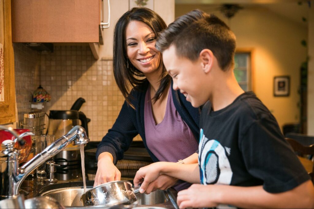 Mom washing dishes with son