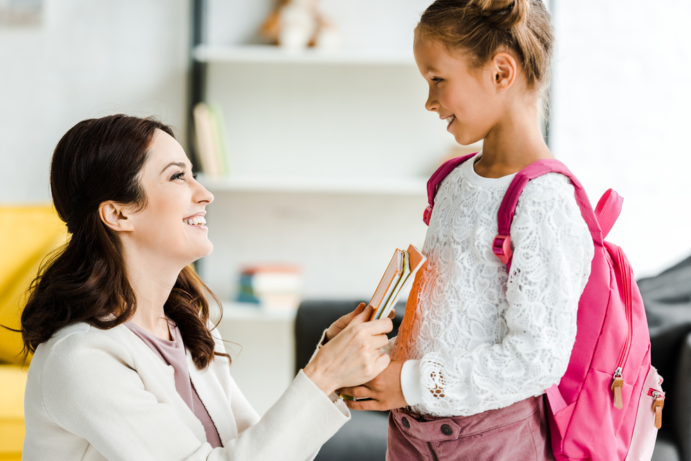 Mom giving books to daughter for school