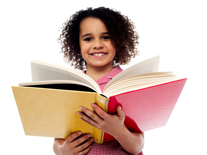 Adorable school girl reading a book with a smile