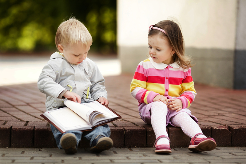 Two kids looking at a Book With Rhyming Words For Kids 
