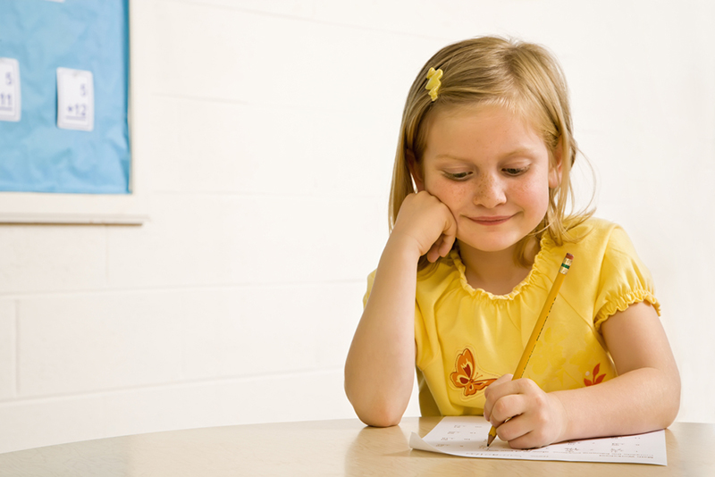 Young girl writing spelling words on paper