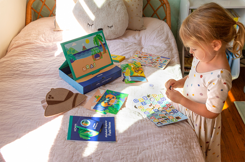 young girl playing with stickers to learn letters