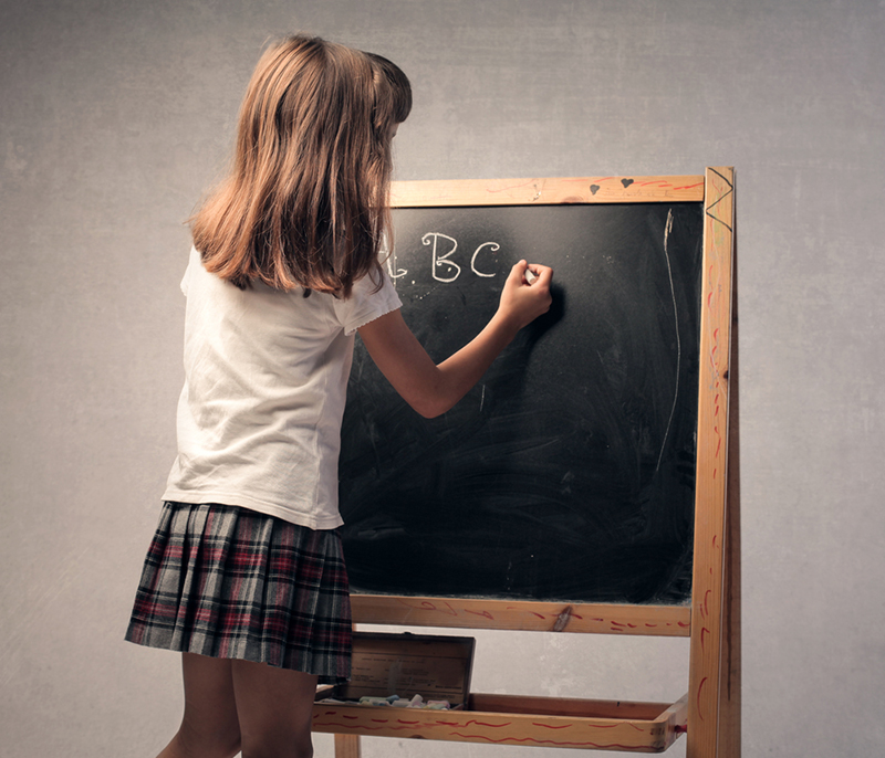 Young girl using a chalkboard to write letters