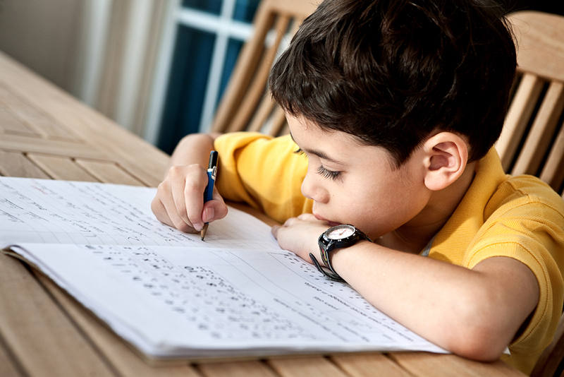 Young boy doing his homework of letter formation.