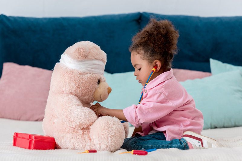 Young girl playing doctor with a teddy bear 