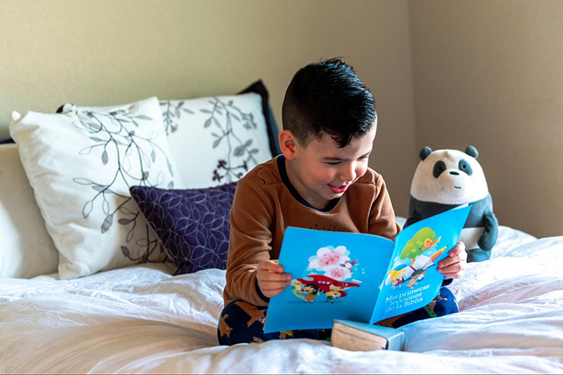 Young boy reading in bed